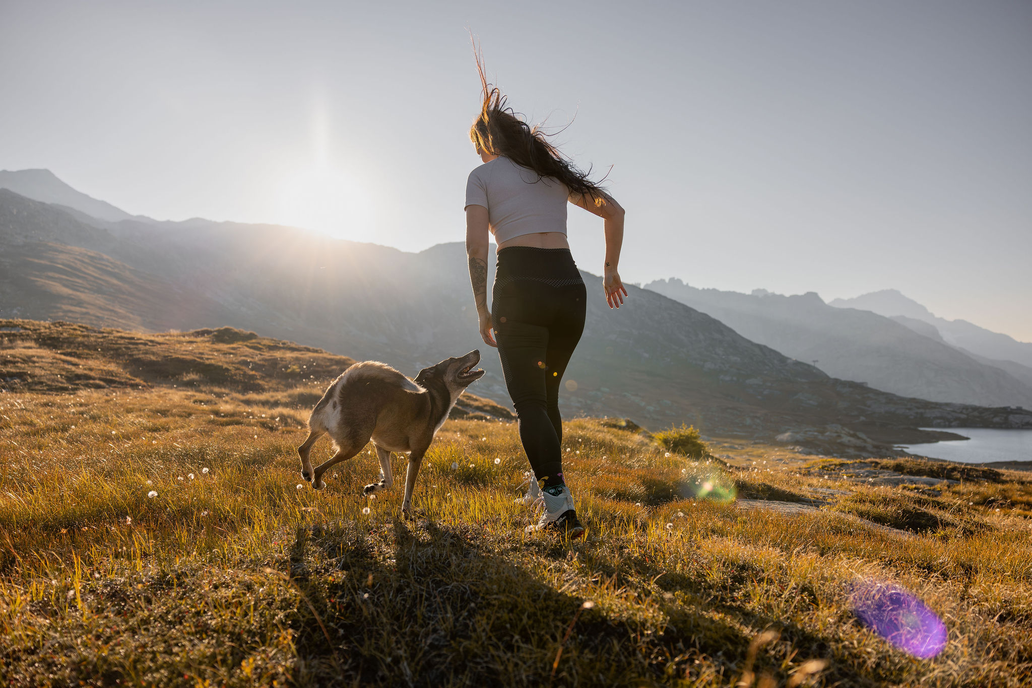 Eine junge Frau joggt mit ihrem Hund in einer Berglandschaft