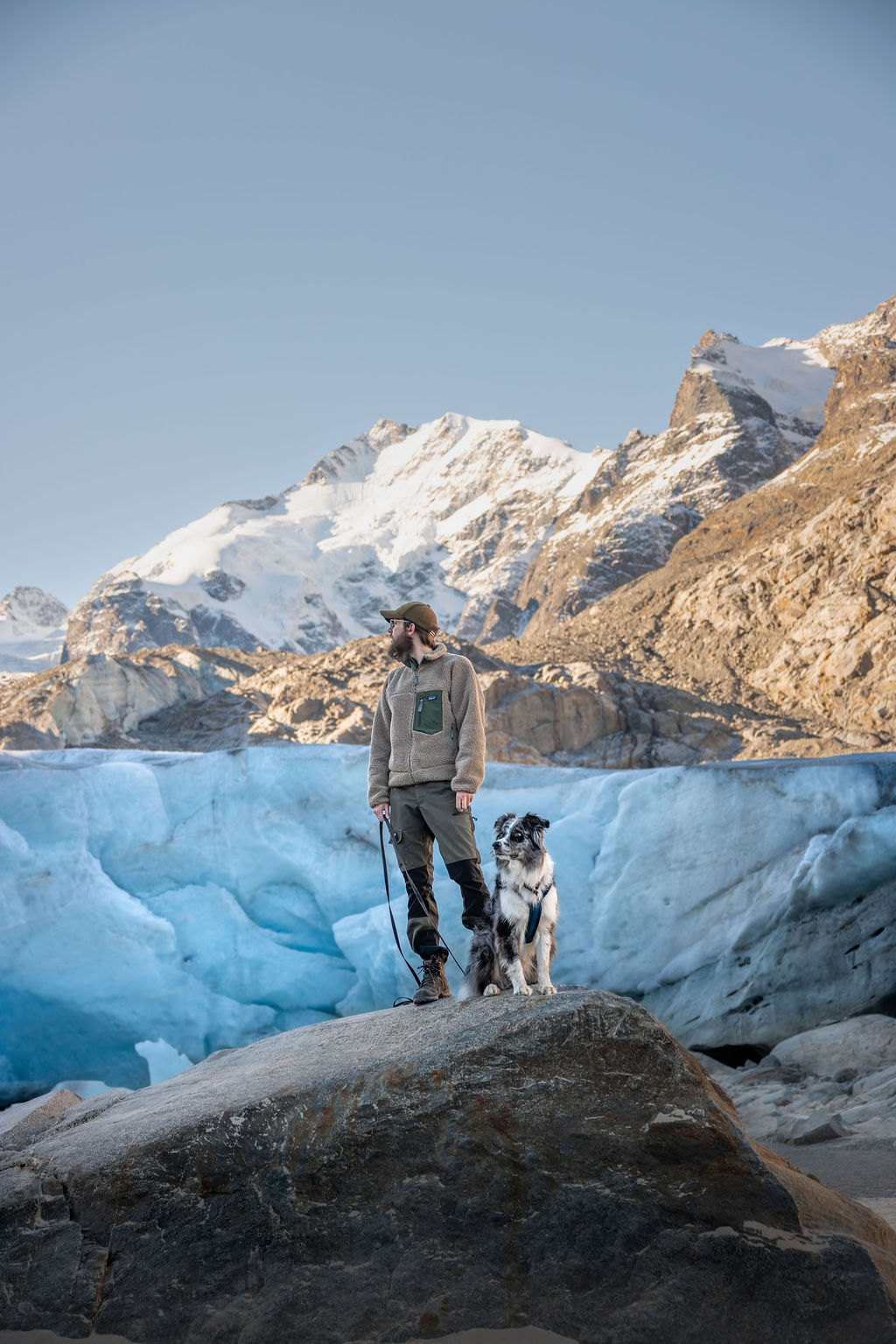Ein Mann und sein Australian Shepherd Hund wandern vor dem Morteratschgletscher im Engadin in der Schweiz